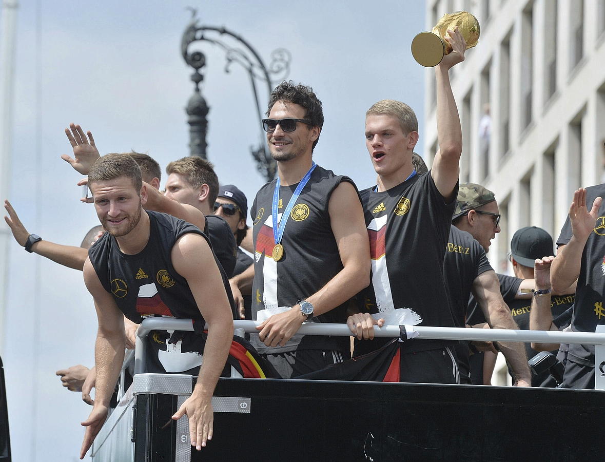 LA SELECCIÓN ALEMANA CELEBRA LA COPA DEL MUNDO CON MILES DE AFICIONADOS. Shkodran Mustafi (i-d), Mats Hummels y Matthias Ginter celebran la Copa del Mundo de la FIFA con cientos de miles de aficionados a su llegada a la Puerta de Brandeburgo a bordo de un autobús sin techo, en Berlín.