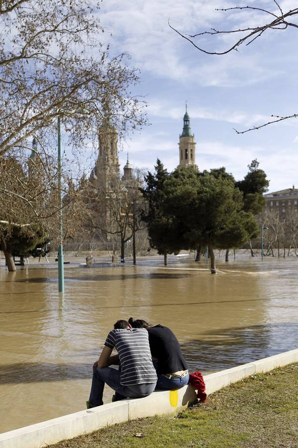 Dos personas en el parque de Macanaz, en Zaragoza, que se encuentra anegado por el caudal del río Ebro.