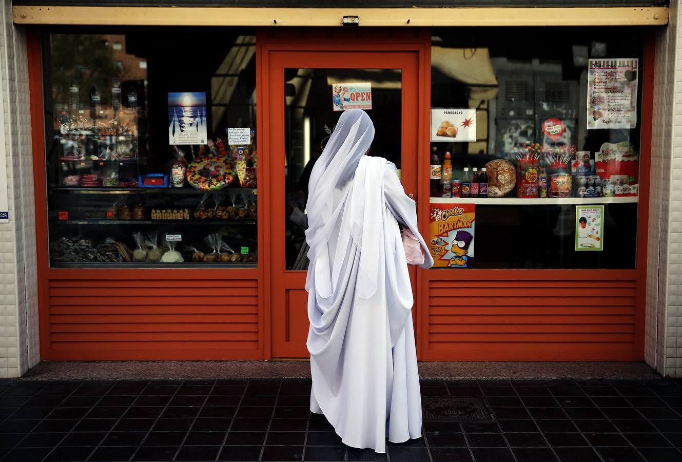 Una mujer disfrazada para el desfile de la Semana Santa Marinera aguarda ante una panadería durante este de este domingo de resurección.