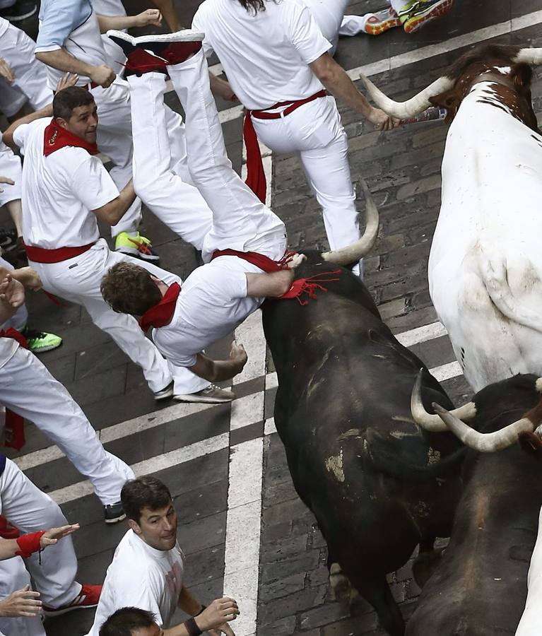 El golpe de un toro eleva en el aire a uno de los mozos.