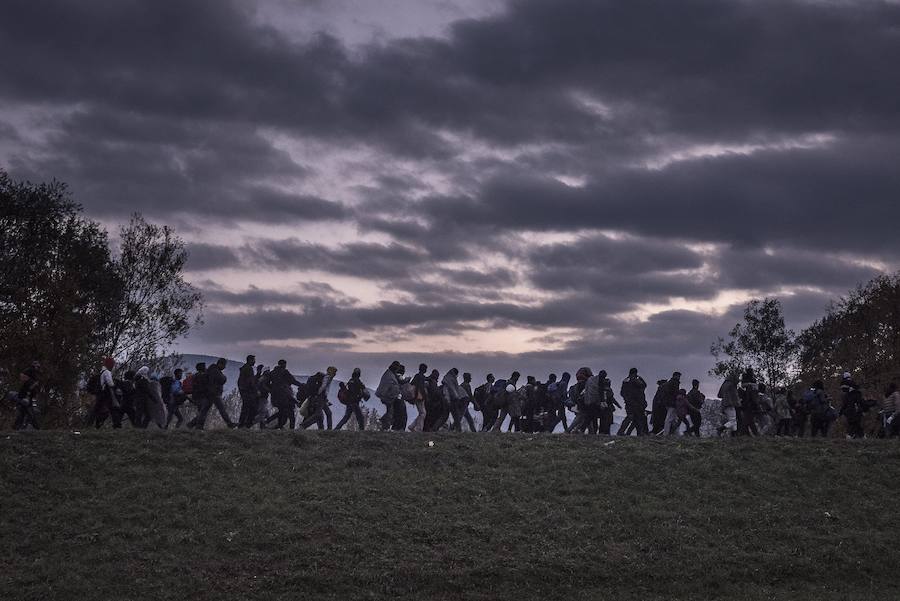 Primer premio de la categoría Temas de Actualidad. La fotografía muestra un grupo de migrantes caminando encima de un dique mientras la policía antidisturbios eslovena los acompaña al campo de registro de Dobova.