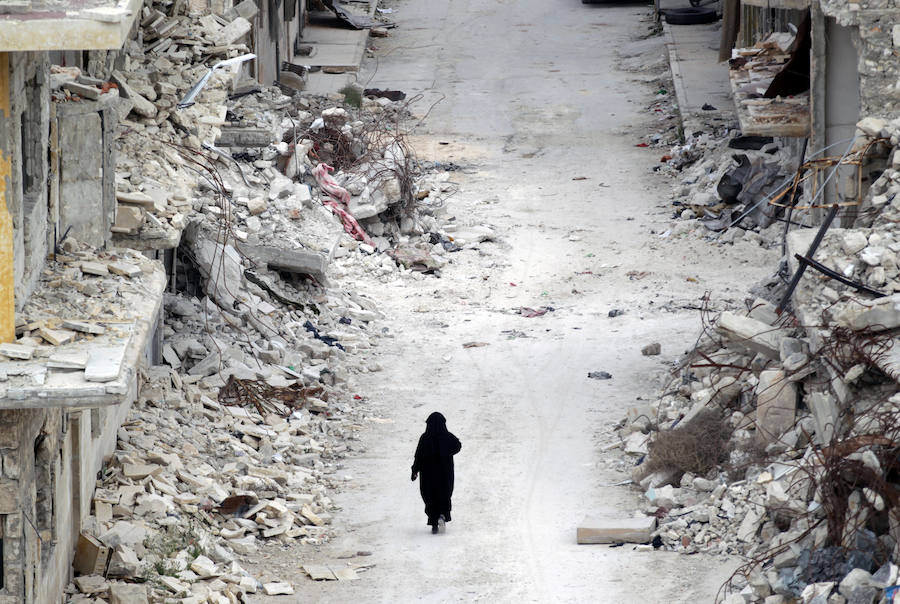 Una mujer pasa junto a edificios dañados en la zona controlada por los rebeldes de la ciudad Maaret al-Numan, en la provincia de Idlib (Siria).