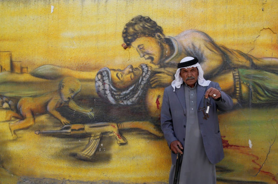 El refugiado palestino Shaher al Khatib, de 76 años, posa delante de un mural por el 68 aniversario de Al Nakba, cerca de la ciudad Cisjordana de Ramala.