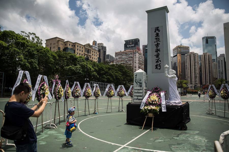 Un hombre toma una foto a un monumento con una pancarta en la que se lee 'Mártires de la democracia nunca morirán' en Hong Kong.