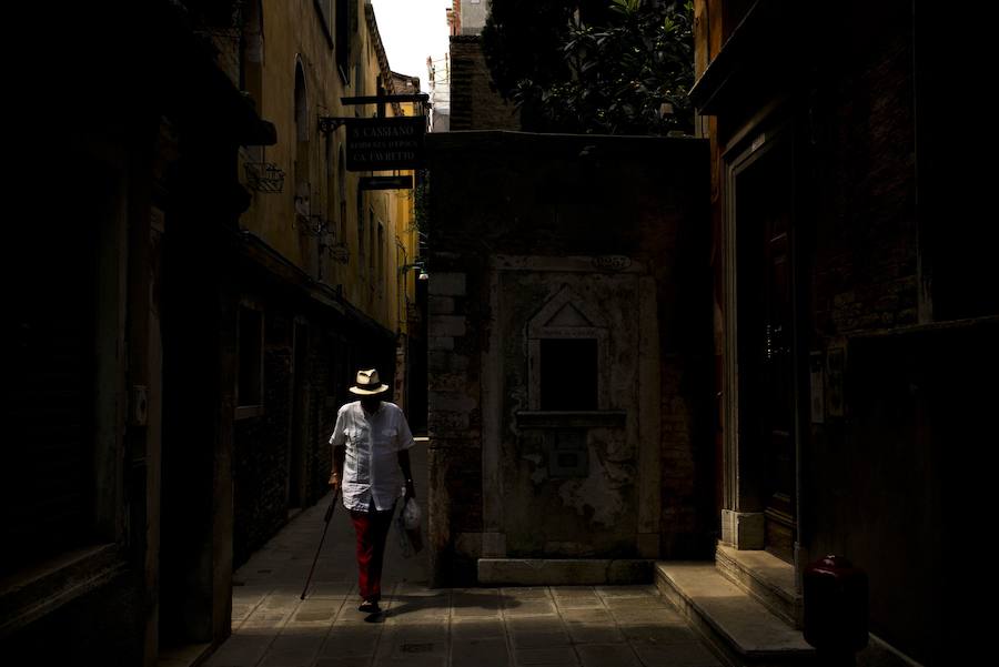 Un hombre camina por una calle estrecha de Venecia.
