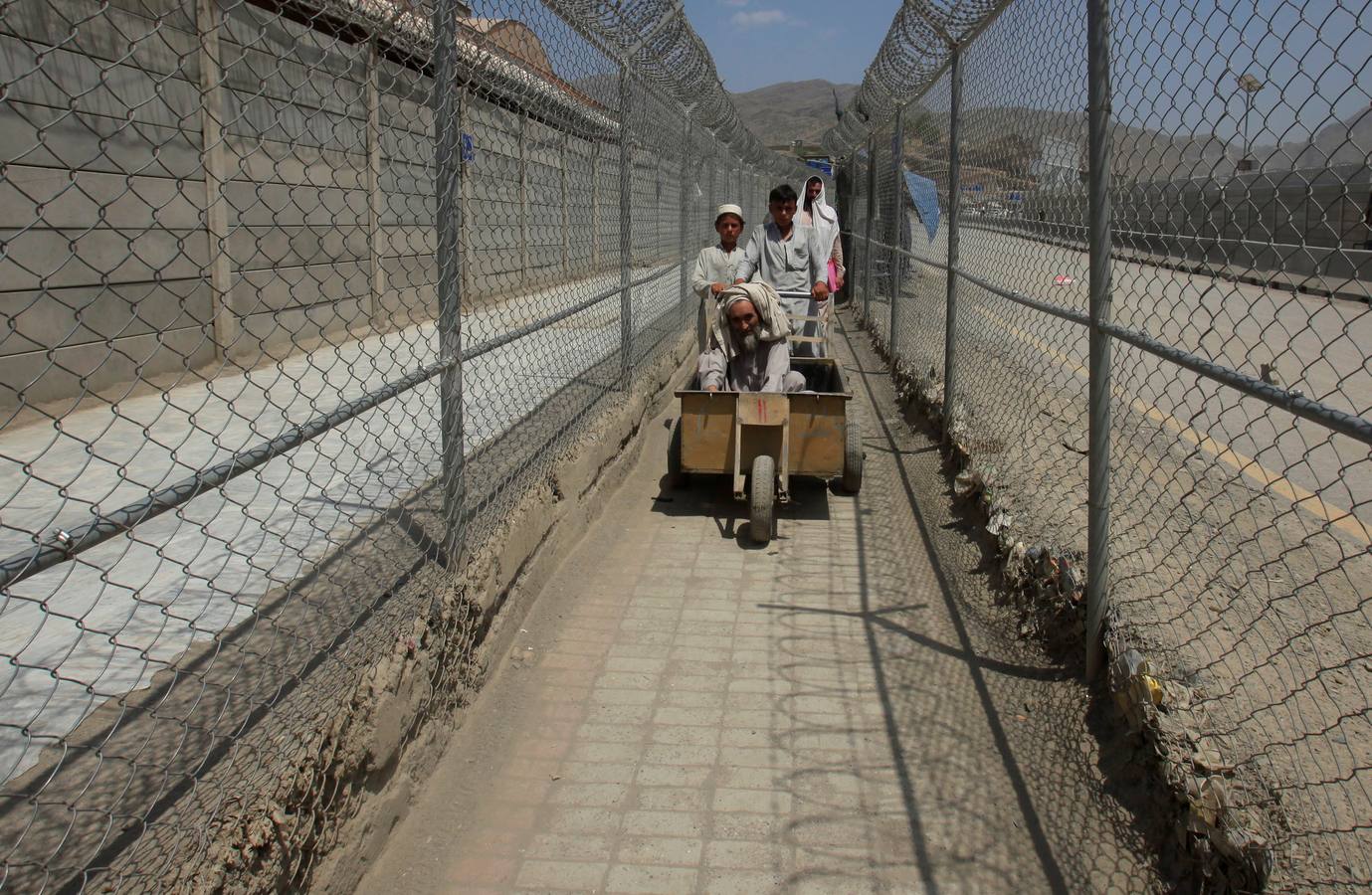 Entre fronteras. Un hombre de avanzada edad, de Afganistán, transportado en un carro por un pasillo entre las vallas de seguridad fronterizas en Torkham (Pakistán).