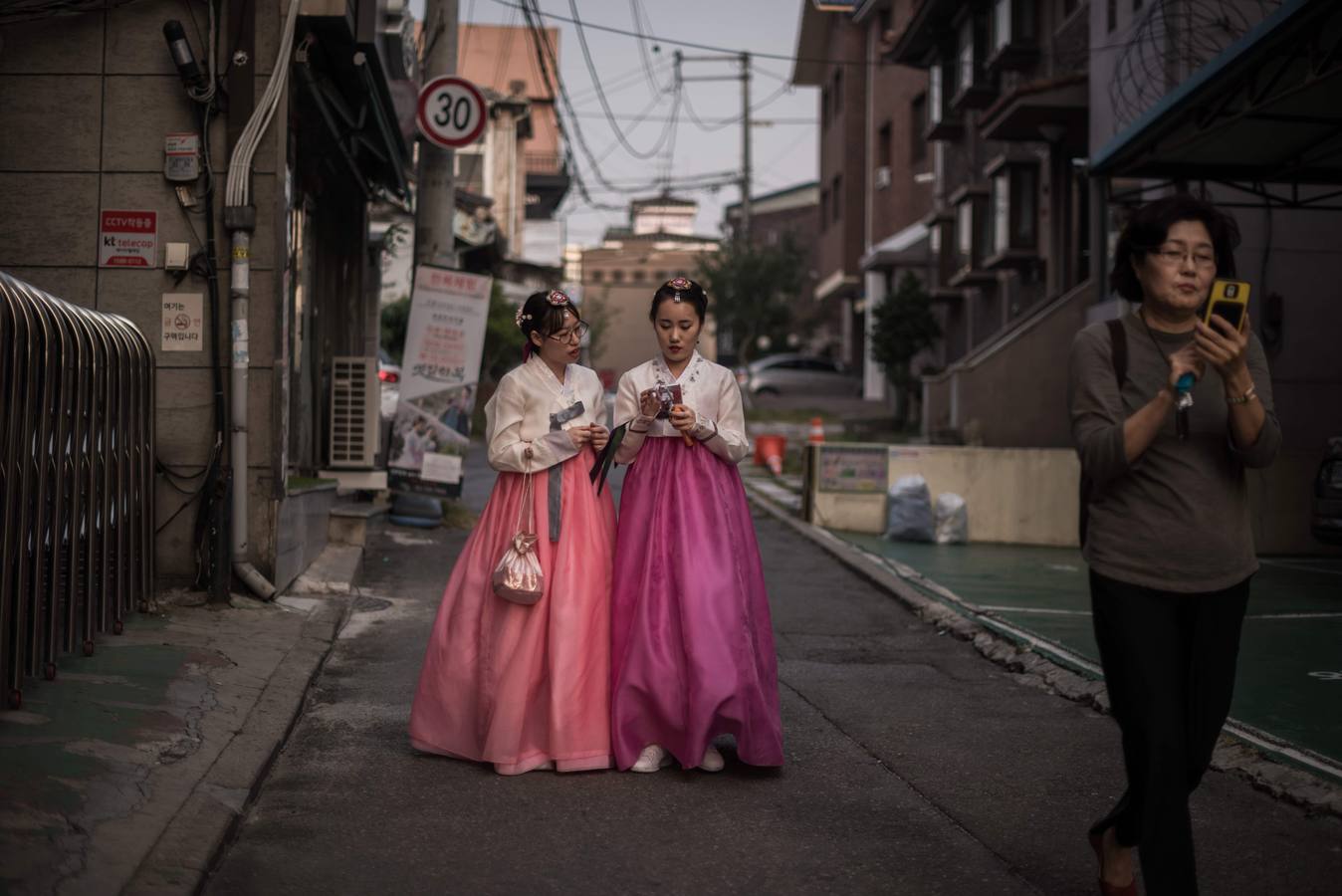 Tradición y modernidad en dos mujeres con vestidos típicos surcoreanos y sus teléfonos móviles, en una calle en Seúl. / AFP PHOTO / Ed Jones