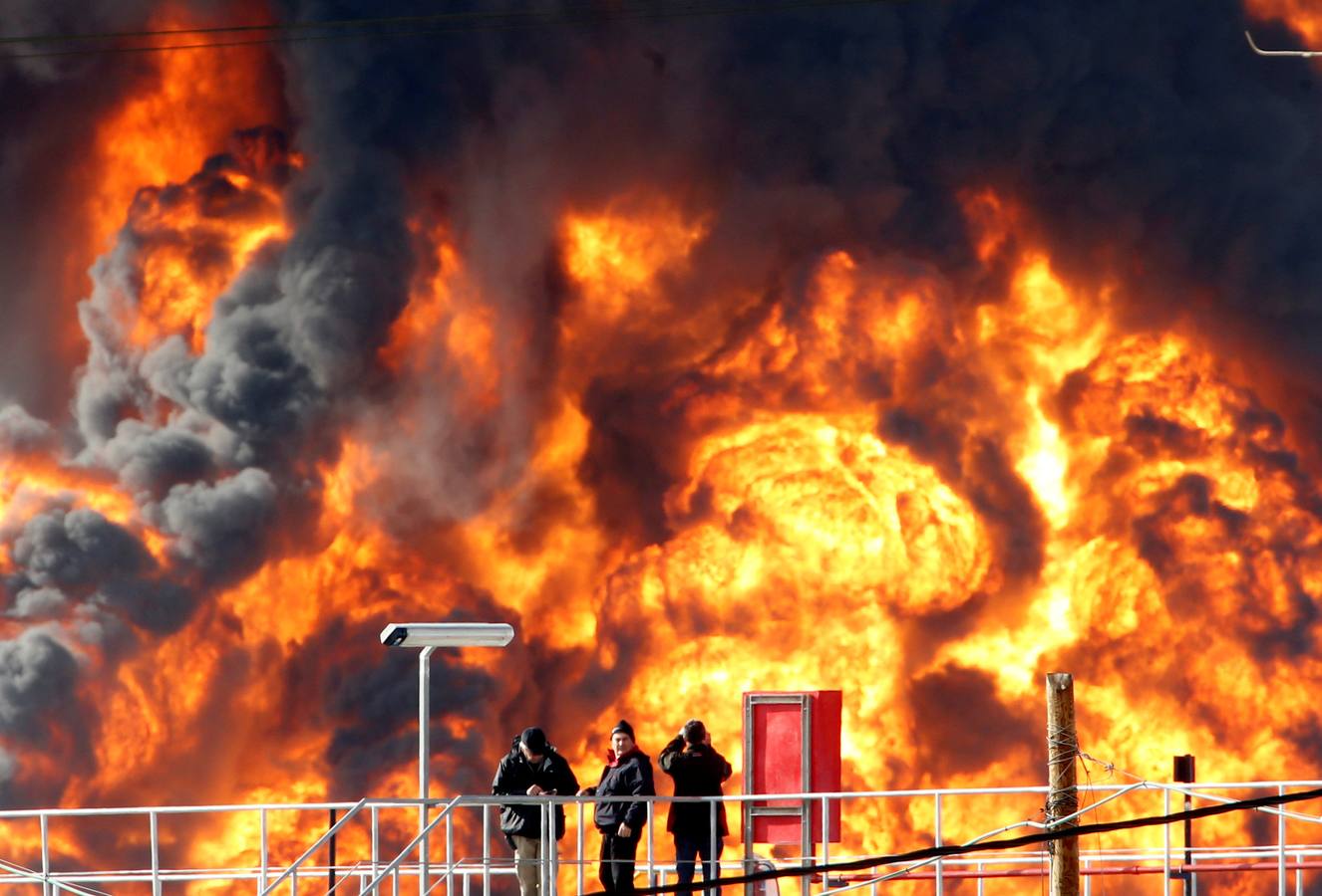 Fuego en Haifa. Tres personas ante las grandes llamas de un tanke incendidao en la refinería de Oil Refineries Ltd en la ciudad israelí de Haifa. REUTERS / Baz Ratner