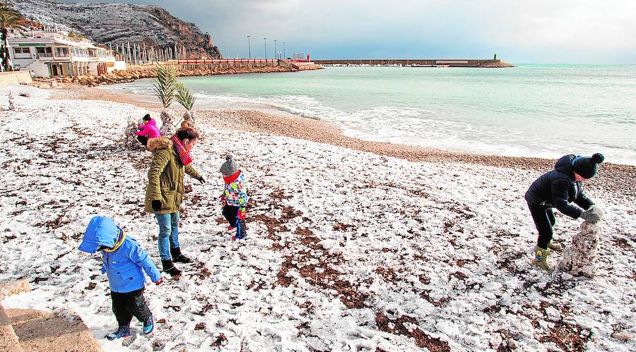 Los niños disfrutan con la nieve en la playa de Xàbia.