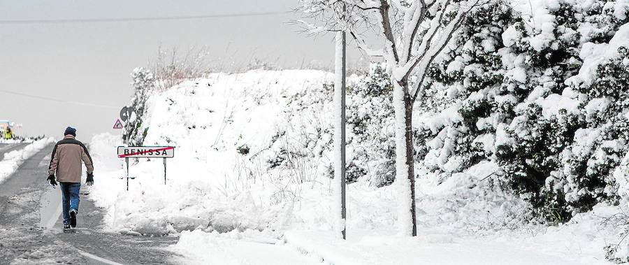 Un vecino circula  por un camino en Benissa en un entorno cubierto por la nieve.