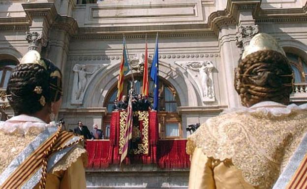 Dos falleras, ante la Senyera y las banderas de España y la UE en el balcón del ayuntamiento de Valencia, en una imagen de archivo.