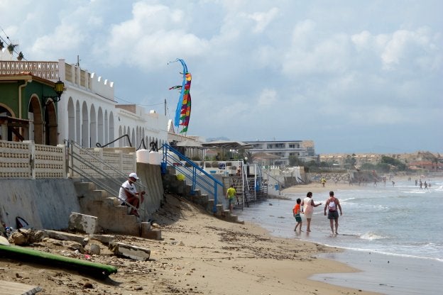 Varias personas pasean tras cesar la lluvia por lo que queda de la playa de Les Deveses, en el litoral norte de Dénia. 