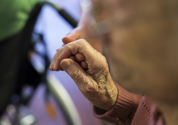 Una enfermera coge de la mano a una residente en un centro de mayores. 