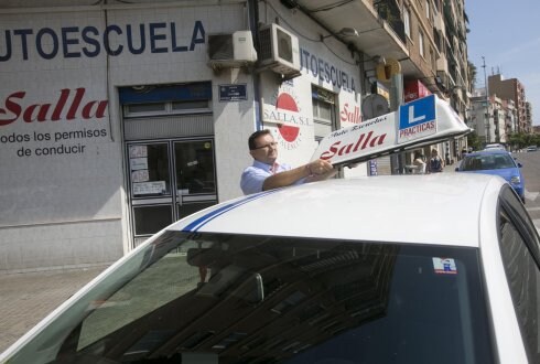 El dueño de la autoescuela Sella coloca el indicativo del vehículo de prácticas. 
