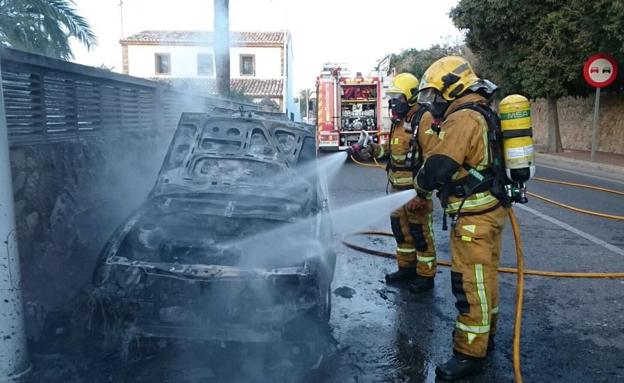 Los bomberos extinguen el fuego en el coche. 