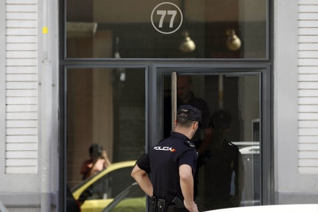 Un policía nacional junto a la puerta del edificio donde el narcotraficante sueco asesinó al subinspector Blas Gámez. 