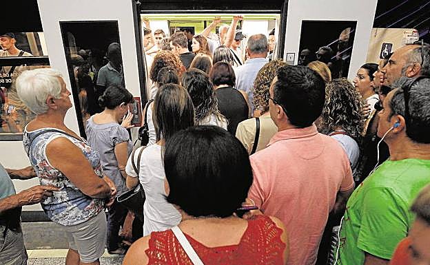 Decenas de personas esperan para subir al metro. 