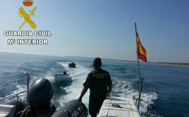 Una embarcación de la Guardia Civil remolca la patera. 