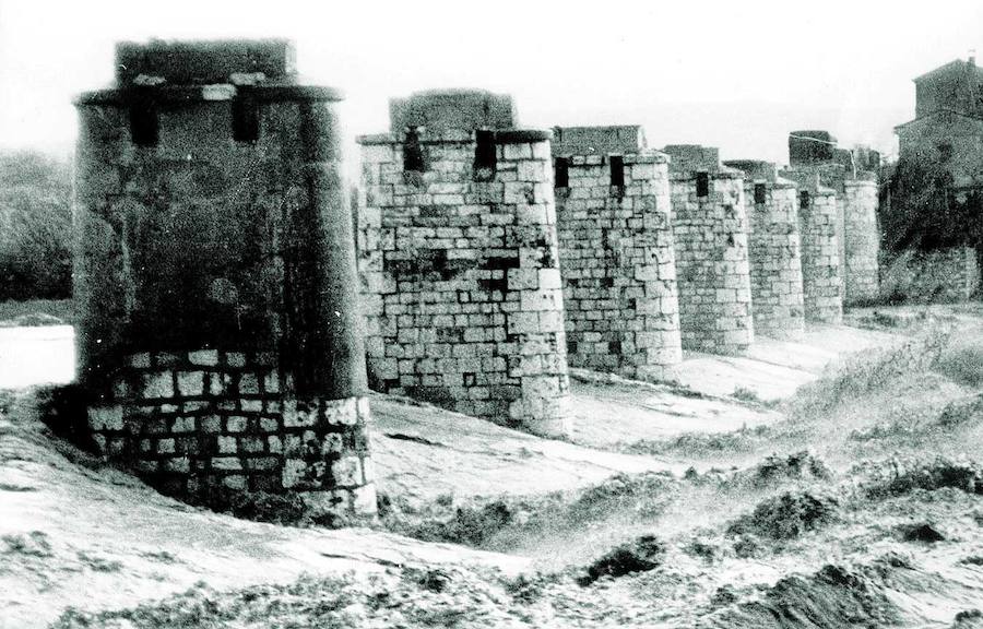 Pilares de una estructura de un puente (parece) que ha desaparecido tras llevársela la fuerza de las aguas. En la base, la corriente de agua formando olas..