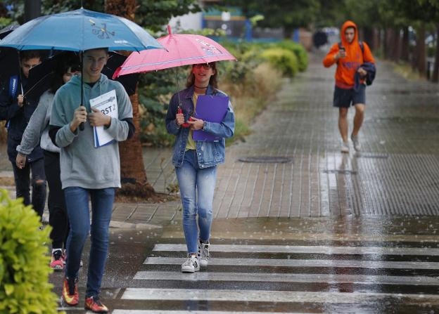 Varios viandantes se protegen de la lluvia ayer en Valencia. 