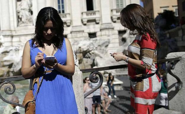 Dos usuarias consultando sus smartphones.