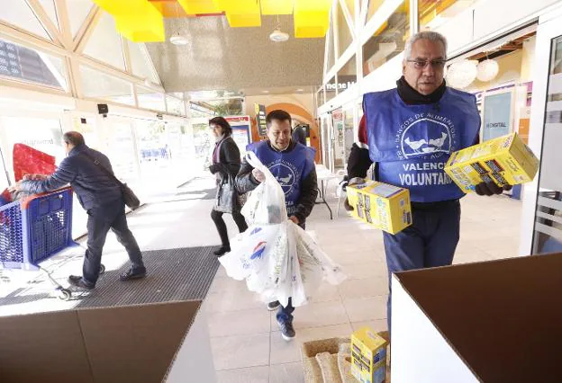 Dos voluntarios al servicio del Banco de Alimentos trasladan comida a las cajas, ayer, en la entrada de un centro comercial. 