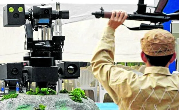 Un soldado de Corea del Sur realiza una demostracón ante un robot de la frontera.