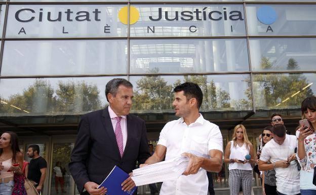 Javier Santos (camisa blanca) muestra la demanda de paternidad en la Ciudad de la Justicia. /