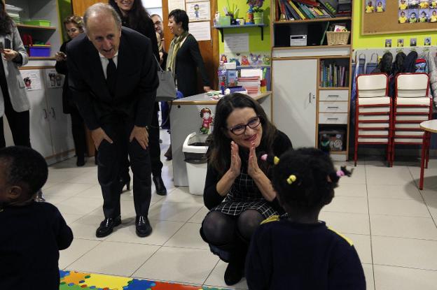 La consellera Mónica Oltra juega con una niña de la escuela infantil de Casa Caridad junto al presidente Luis Miralles, ayer. 