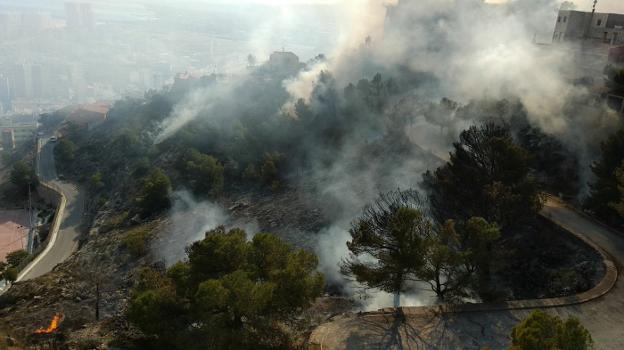 Llamas y humo por el incendio forestal que se declaró el lunes en la montaña de Cullera, ya extinguido. 