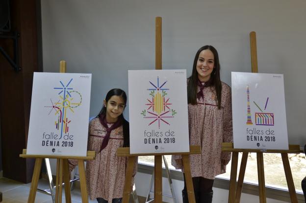 Las falleras mayores de Dénia junto a tres de los carteles. 