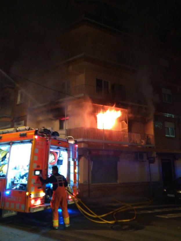 El fuego sale por el balcón de la vivienda afectada. 