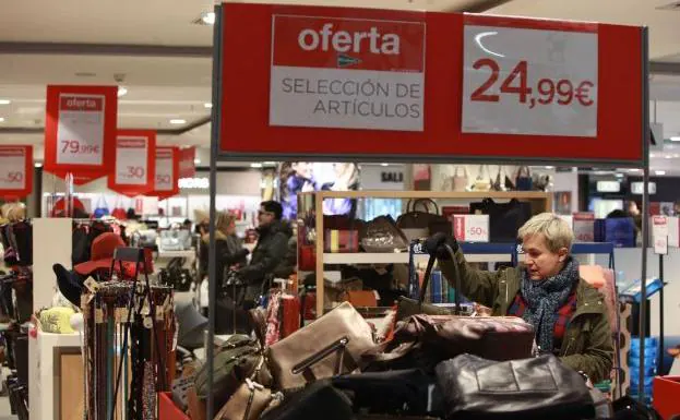 Una mujer busca bolsos rebajados en un centro comercial.