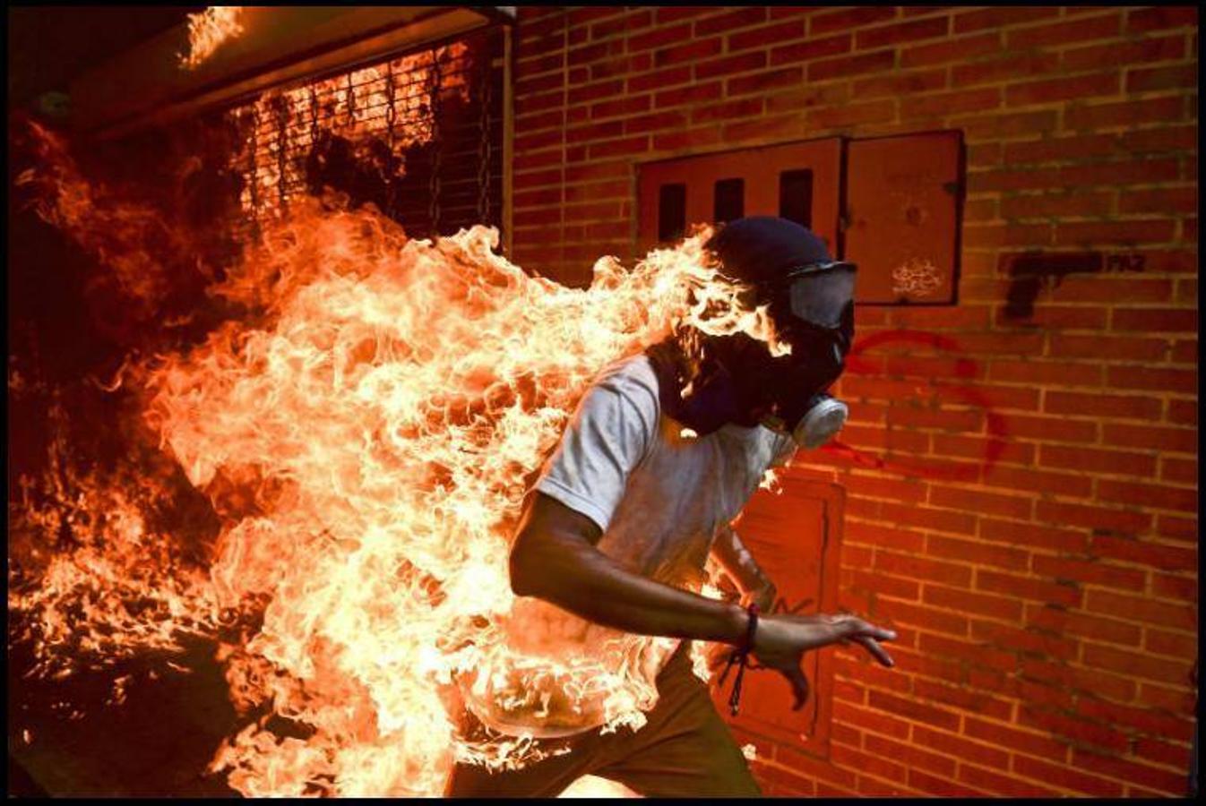 Romaldo Schemidt. 3 de mayo de 2017. La imagen se produjo durante unos enfrentamientos con la policía venezona en Caracas (Venezuela), en una protesta contra el presidente Nicolás Maduro. El joven, que fue prendido en llamas accidentalmente, corre en busca de ayuda para apagar el fuego. 