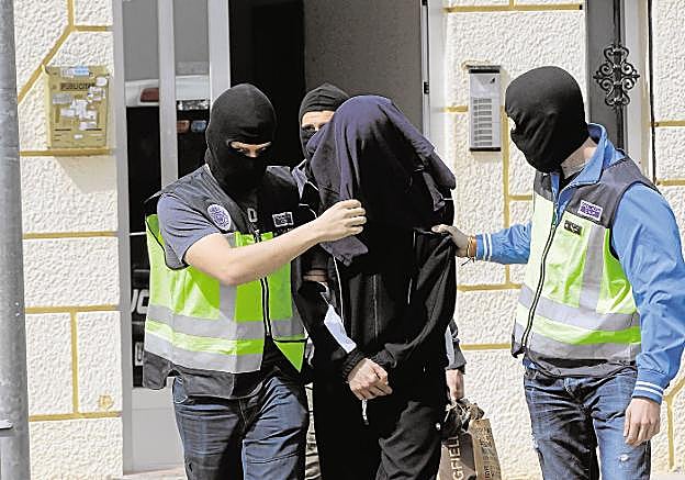 Policías nacionales, con un hombre detenido por reclutar a islamistas en Valencia. 