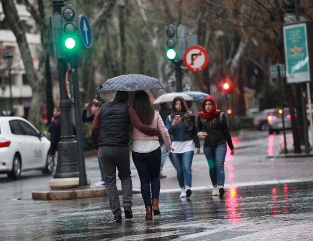 Varias personas caminan con paraguas por las calles de Valencia, ayer, durante el paso de la tormenta por la ciudad. 
