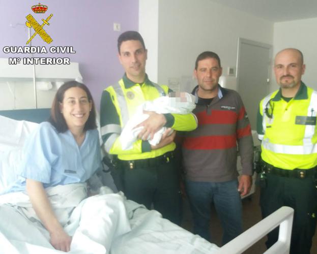 El recién nacido, con sus padres y los guardias civiles que los asistieron, posan en el hospital La Fe.