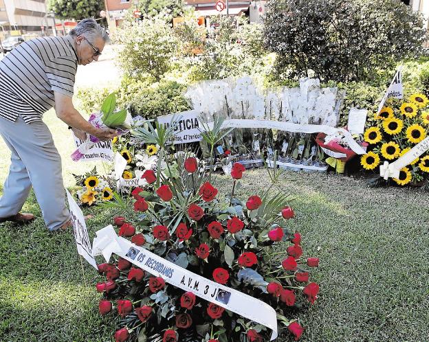 Un hombre coloca flores en recuerdo de las víctimas. 