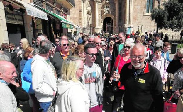 Un guía dirige a un grupo de turistas frente a la Catedral de Valencia.