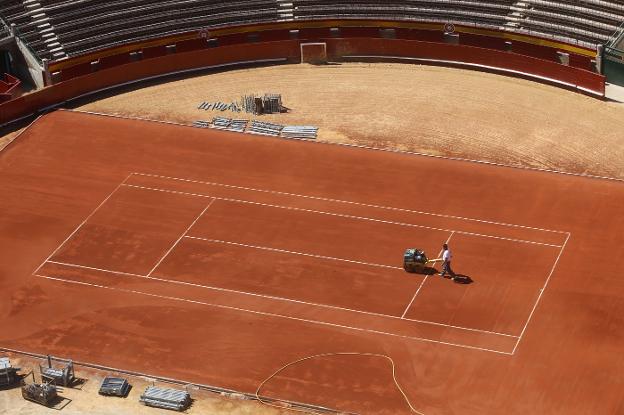 Un operario pinta las líneas de la pista de tenis de la Plaza de Toros de Valencia. 