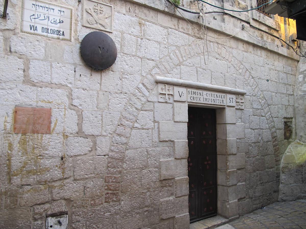 ESTACIÓN V DEL VIACRUCIS | Una inscripción en el arquitrabe de una puerta indica el lugar del encuentro entre Jesús y Simón el Cirineo, que fue quien le ayudó a llevar la pesada cruz tras la primera caída. En la pared se observa una marca, que según la tradición está hecha por el propio Jesús al apoyarse durante el ascenso al Gólgota.
