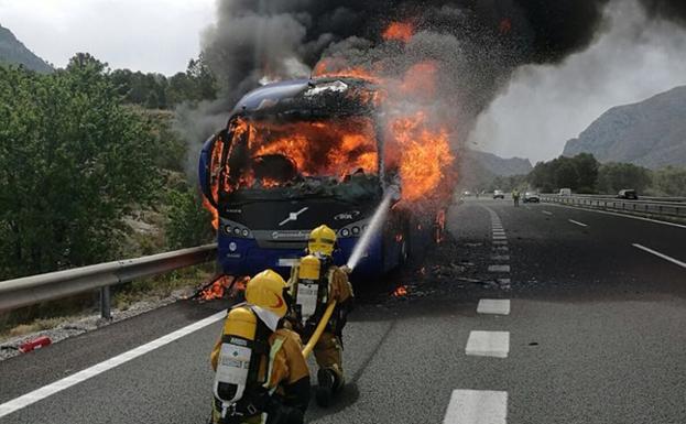 Los bomberos, atacando las llamas del autobús incendiado.