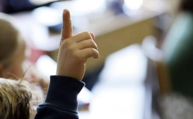 Un niño levanta la mano en una clase de Infantil. 