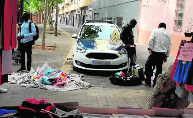 Manteros junto a un coche policial en el mercadillo de Jesús, este sábado. 