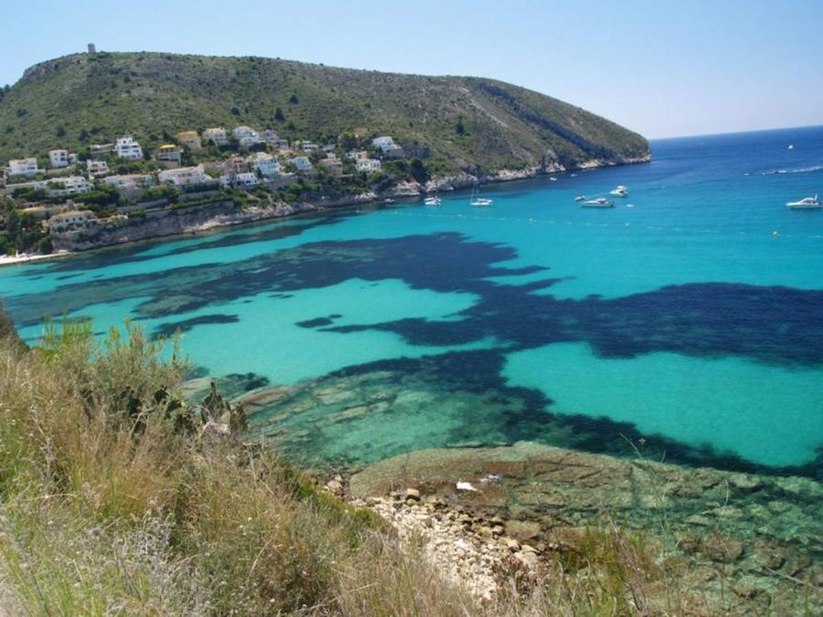 Cala El Portet, Moraira. Una playa de poca profundidad y de aguas muy tranquilas. Tiene una oferta de ocio muy amplia, con varios restaurantes y cafeterías para refrescarte y descansar del sol. 