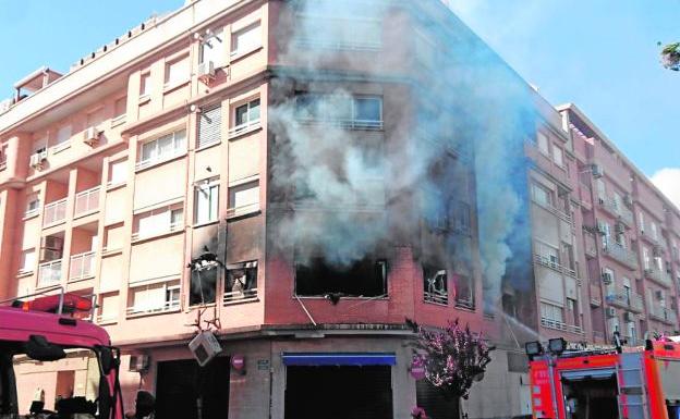 Bomberos ante la vivienda incendiada.