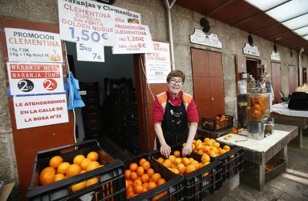 Rosa Remolar, en su parada de naranjas en el Mercado de Santiago y su máquina de zumo en primera línea. 