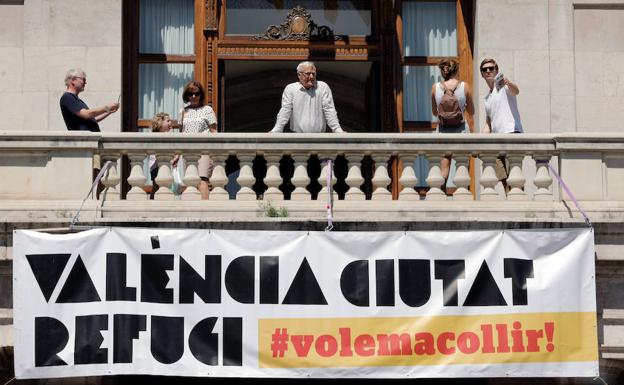 Valencia cuelga el cartel de 'Ciudad Refugio' en el balcón del Ayuntamiento