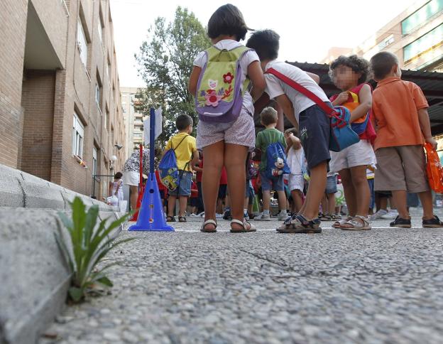 Unos niños esperan a subir en un autobús. 