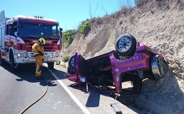 El vehículo volcado, junto a un bombero de Consorcio de Alicante.